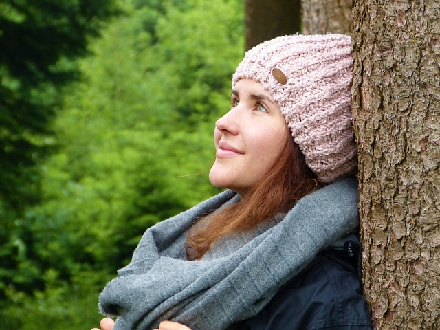 The real roots of anxiety - A women leaning against a tree in the forest wearing a knitted winter hat