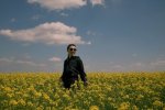  Do more than survive - thrive: A women wearing sunglasses waking through a meadow of yellow flowers