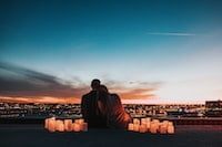 man, and women in love sitting overlooking a city with candles on either side of them - Love and PTSD