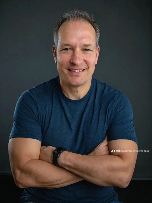 Author/speaker/trained counsellor, Jonathan Arenburg posing in a blue shirt with arms crossed.